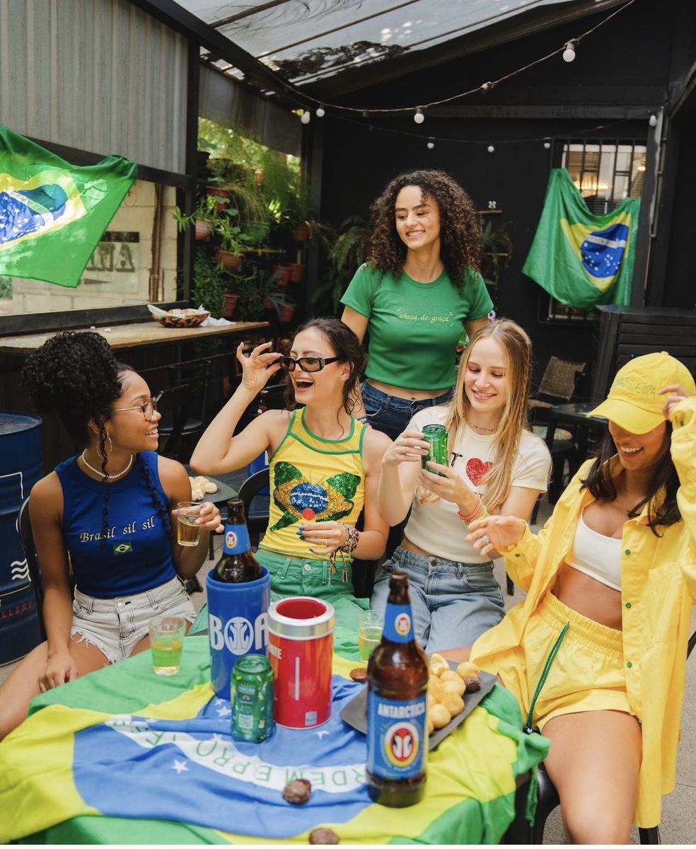 Grupo de amigas brindando com bandeira do Brasil na mesa